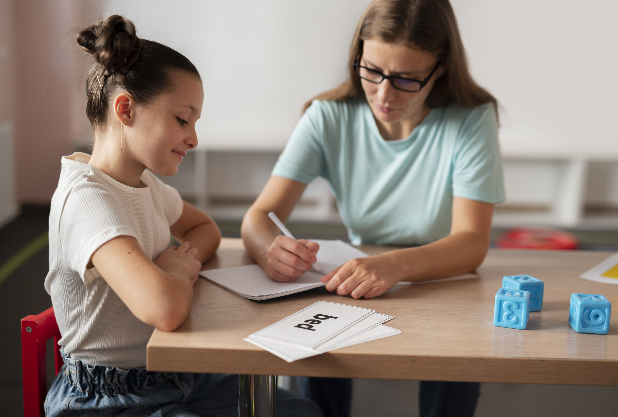 Female speech-language pathologist providing speech therapy session to a young girl